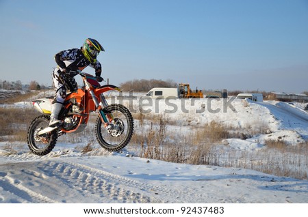 Motorcycling rider on a motorcycle motocross jumps from a hill on a snowy highway