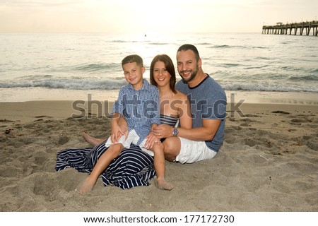 Beautiful brunette family smiling at the beach at sunrise