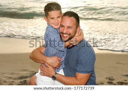 Handsome brunette father and son hugging at the beach at sunrise