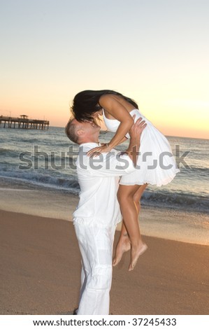 Brunette Couple in love at the beach at sunrise