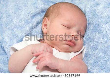 Beautiful sleeping newborn baby boy on blue blanket