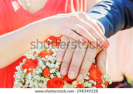 Groom and bride hands and rings on wedding bouquet