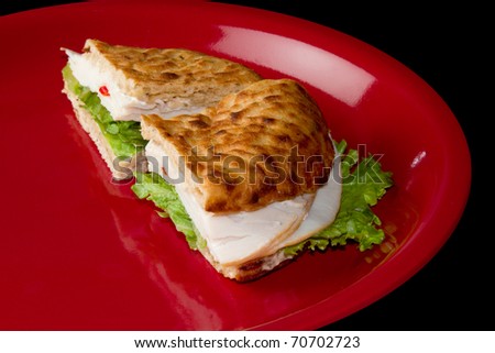 Healthy Turkey Deli Sandwich on a Red Plate with a Black Background
