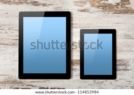tablet computer and mini tablet with isolated screen on a background of wood