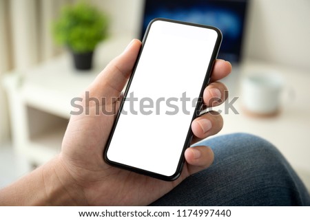 man on sofa holding phone with isolated screen in the room of house