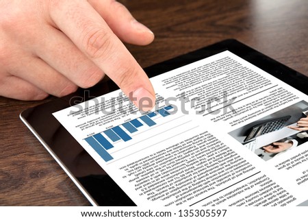 male hand touching computer tablet with business news on screen male hand touching computer tablet with business news on screen
