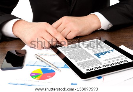 businessman in the office at the table watching business news on tablet computer screen