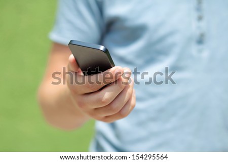 boy holding a touch phone against a green wall