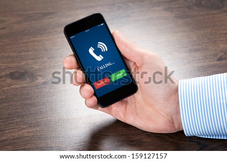 Businessman Holding A Touch Phone With Blue Screen And The Phone Ringing Tube Over The Villages Table