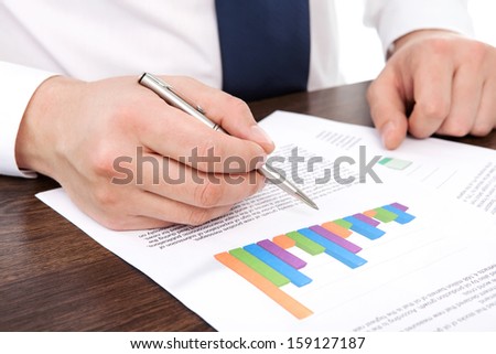 businessman in the office of the table points to the graphics