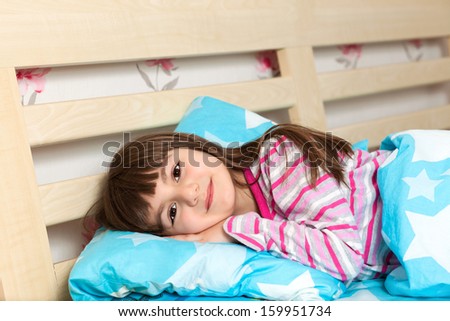 beautiful little girl in pajamas sleep in bed under a blue blanket