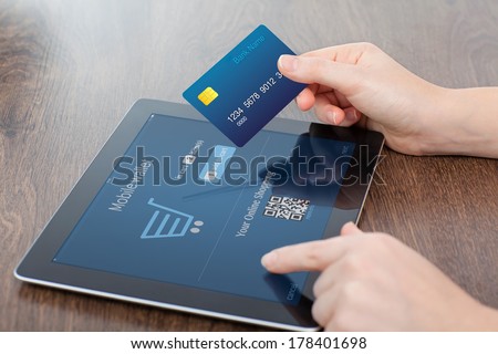 female hands holding credit card and a computer tablet on the table in the office and making a purchase onlain