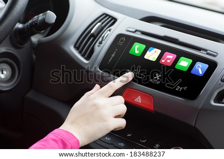 woman sitting in a car with her finger touching electronic controls.
