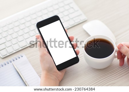 Women hands holding the phone with isolated screen and cup of coffee in the office