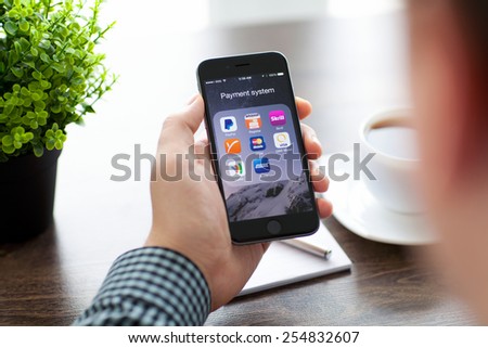 Alushta, Russia - November 20, 2014: Businessman holding iPhone 6 Space Gray with a set of famous brands of payment system on the screen. iPhone 6 was created and developed by the Apple inc.
