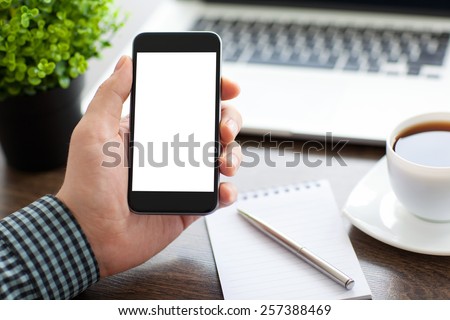 man holding a phone with isolated screen over the desk in the office