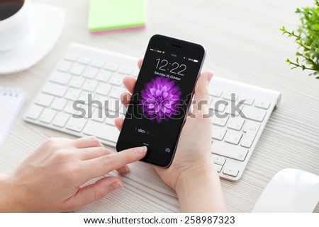 Alushta, Russia - October 25, 2014: Woman unlock her phone iPhone 6 Space Gray over the table. iPhone 6 was created and developed by the Apple inc.