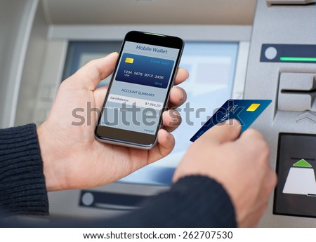 man holding the phone with mobile wallet and credit card on the screen against the background of the ATM