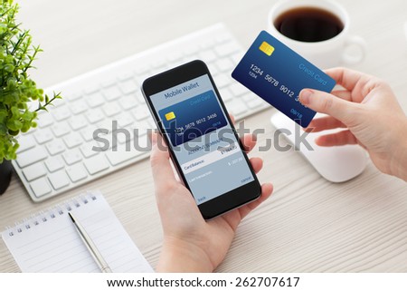 female hands holding phone with mobile wallet for online shopping over the desk