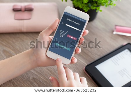female hands holding white phone with online shopping on the screen and e-rider on the women table