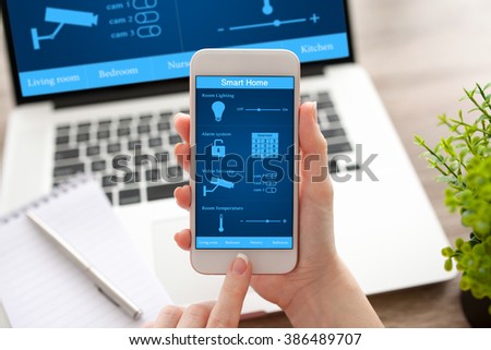 woman hands holding white phone and notebook with app smart home on the screen