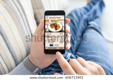 man lying on sofa and holding phone with app delivery food screen