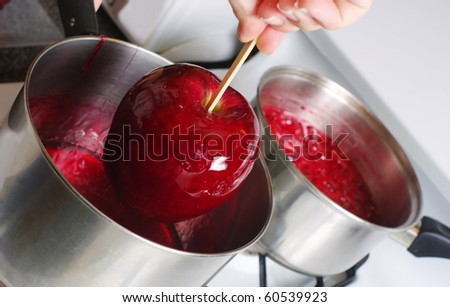 cooking a candied apple, coating it with red syrup