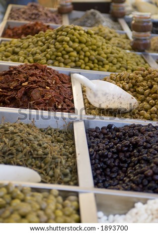 Different types of pickled olives and garlic at an open market in Italy