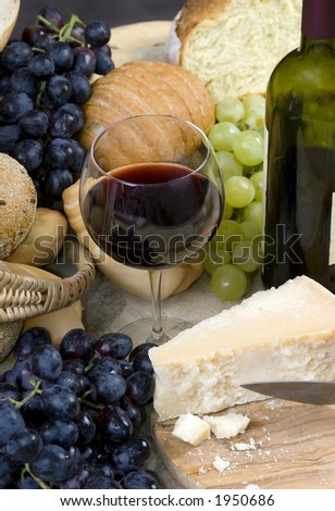 A glass of Chianti wine with assorted breads, cheese and grapes