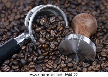 Roasted coffee surrounds a tamper and filter...it\'s coffee time...
