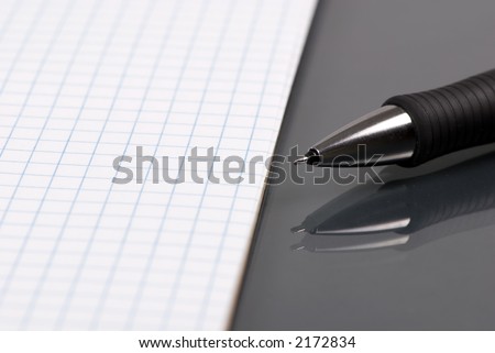 A blank piece of paper with a pen laying on the side. The reflection of the pen can be seen on the desktop.
