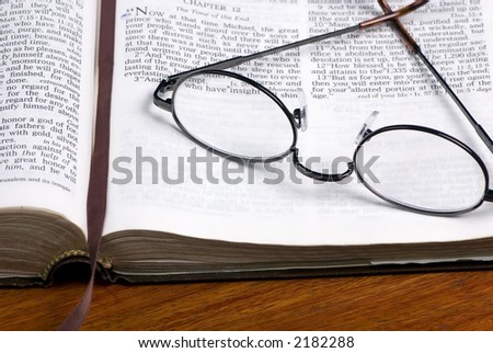 A pair of glasses lays on top of a well read bible