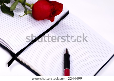 A personal diary is open and ready for the day\'s entry. A single red rose lays on top of the diary...a gift..