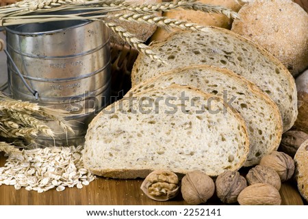 An assortment of whole grain wheat breads on a table. An old time flour shifter sits at the side.