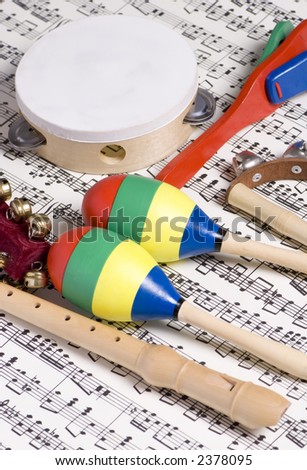 Colorful children's instruments laying on top of a complicated musical score