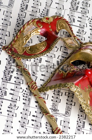 Two masks lay on top of a score of complicated music. Musical love