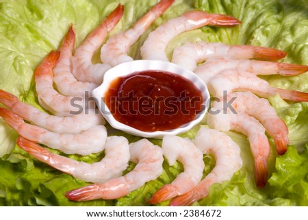 A circle of shrimp cocktail on a lettuce bed