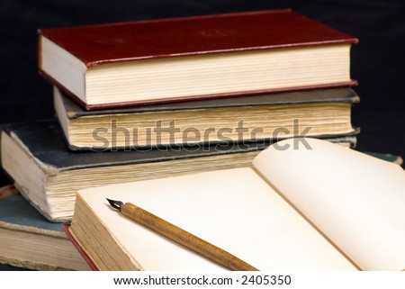 A pile of old books with one open in the front to a blank page