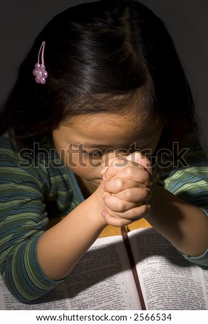 stock photo A young Asian girl praying on a bible