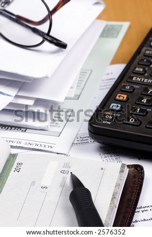 A pile of bills on a table and the checkbook is out...but is there enough money in the account?