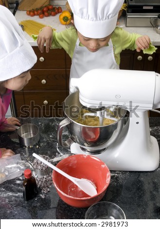 Two young sisters have fun in the kitchen making a mess....I mean making cookies. Education, learning, cooking, childhood
