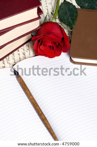A red rose lays on top of a hand written document with a pile of books