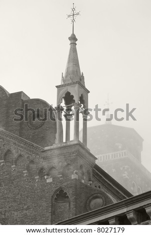 A tall church tower in Venice, Italy, rises above the fog.