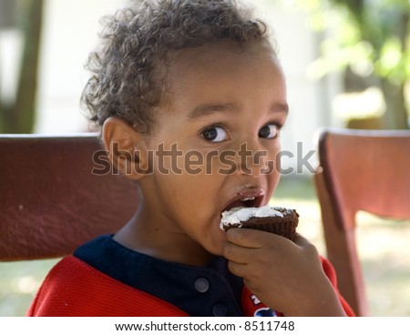 A young african american boy eating birthday cake.