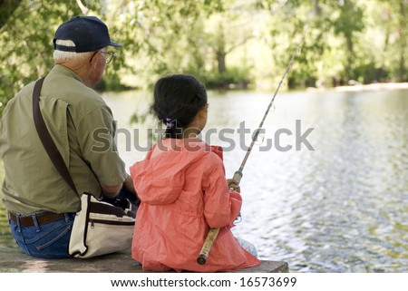 A young girl is fishing with her grandpa on a warm summer day.