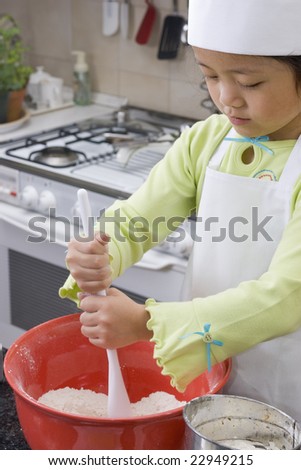A young asian girl cooking up something in the kitchen.