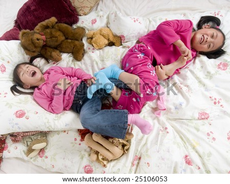Two sisters playing on the bed, tickling feet.
