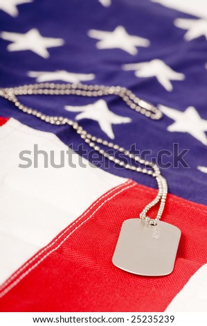 A lone dog tag sits on top of an American Flag