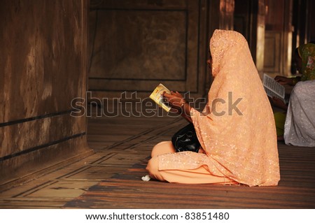 OLD DELHI, INDIA - OCTOBER 25: Muslim women reads a prayer book in mosque Jama Masjid on October 25, 2010 in Delhi, India. Jammu Masjid is the largest mosque in India.