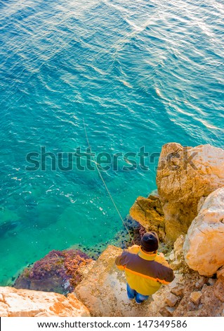 amateur fisherman fishing over the stones in the sea beside Nafplio city in Greece
